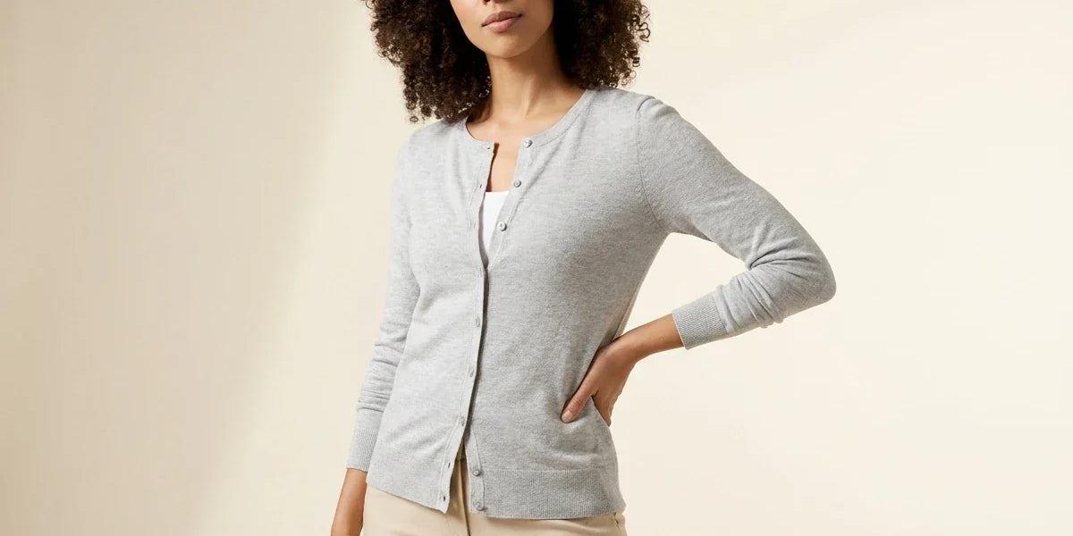 Woman with curly dark hair modeling a Charter Club light grey button-front cardigan sweater over a white top and beige trousers.