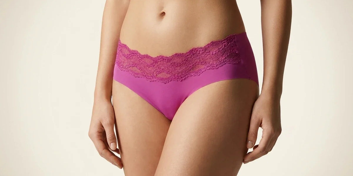 Cropped view of a woman modeling vibrant magenta purple hipster underwear with a wide scalloped floral lace waistband.