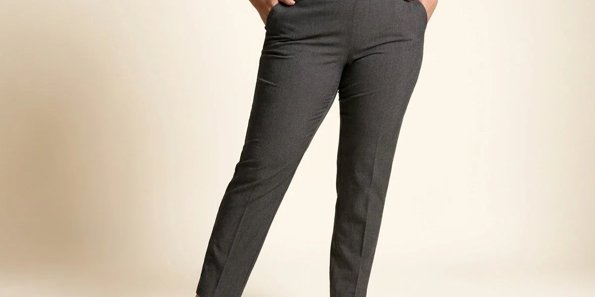 Cropped view of a woman wearing charcoal grey slim-leg tummy-control dress pants paired with pointed black leather loafers and a white button-down shirt.