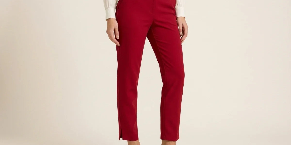 Cropped view of a woman wearing red slim-fit pull-on ankle trousers with side hem slits, styled with black slingback heels and a cream blouse.