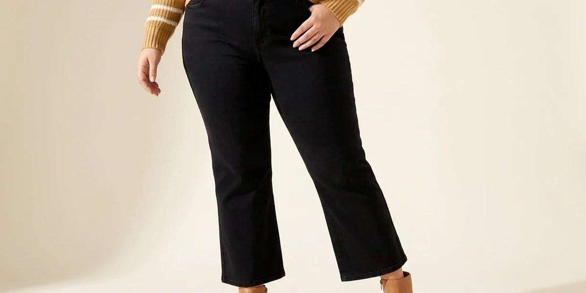 Cropped view of a woman wearing plus-size black cropped flare jeans with tan leather ankle boots and a striped sweater.