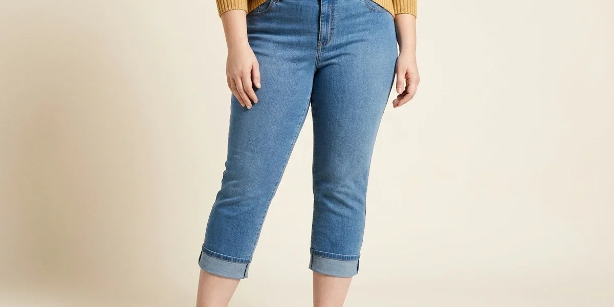 Cropped view of a woman wearing plus-size medium wash cuffed capri jeans with brown leather loafers and a striped knit sweater.
