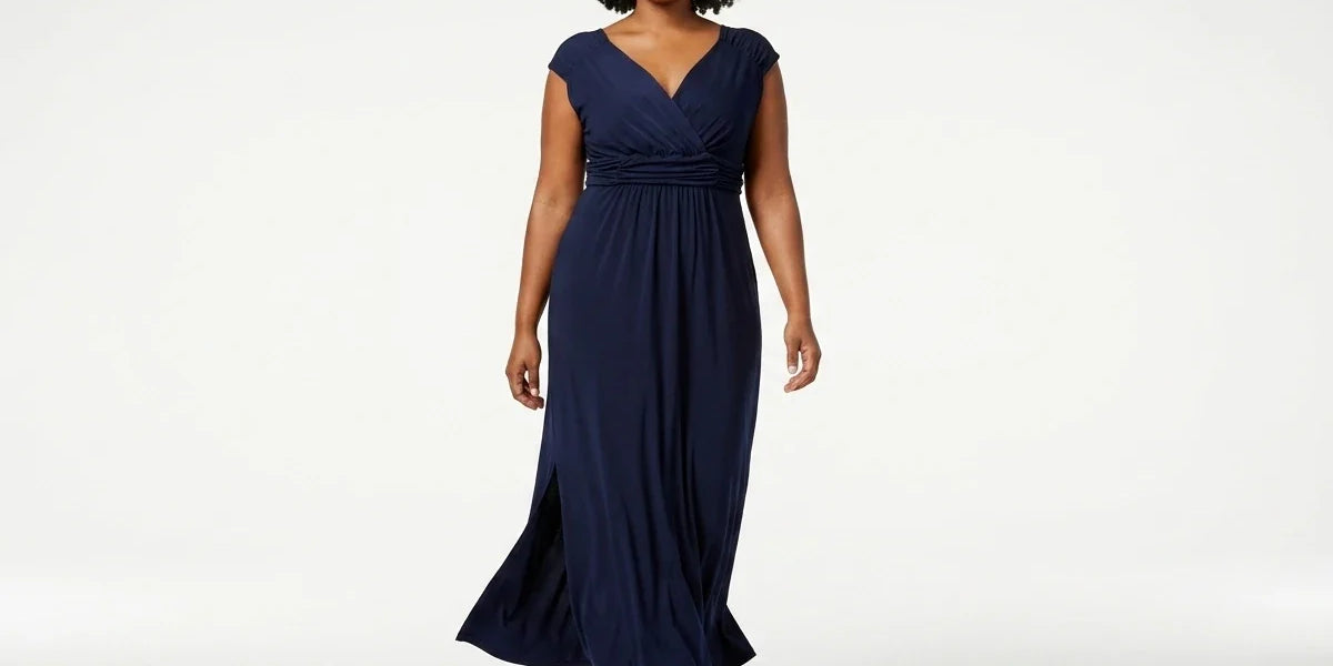A woman modeling a navy blue maxi dress with a V-neckline, cap sleeves, and a gathered waist, photographed against a clean white studio background.