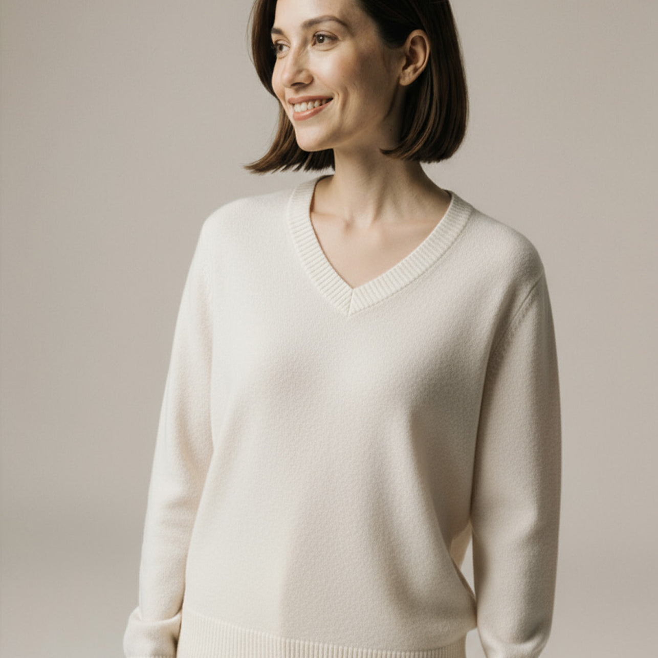 Woman wearing a beige sweater against a plain background