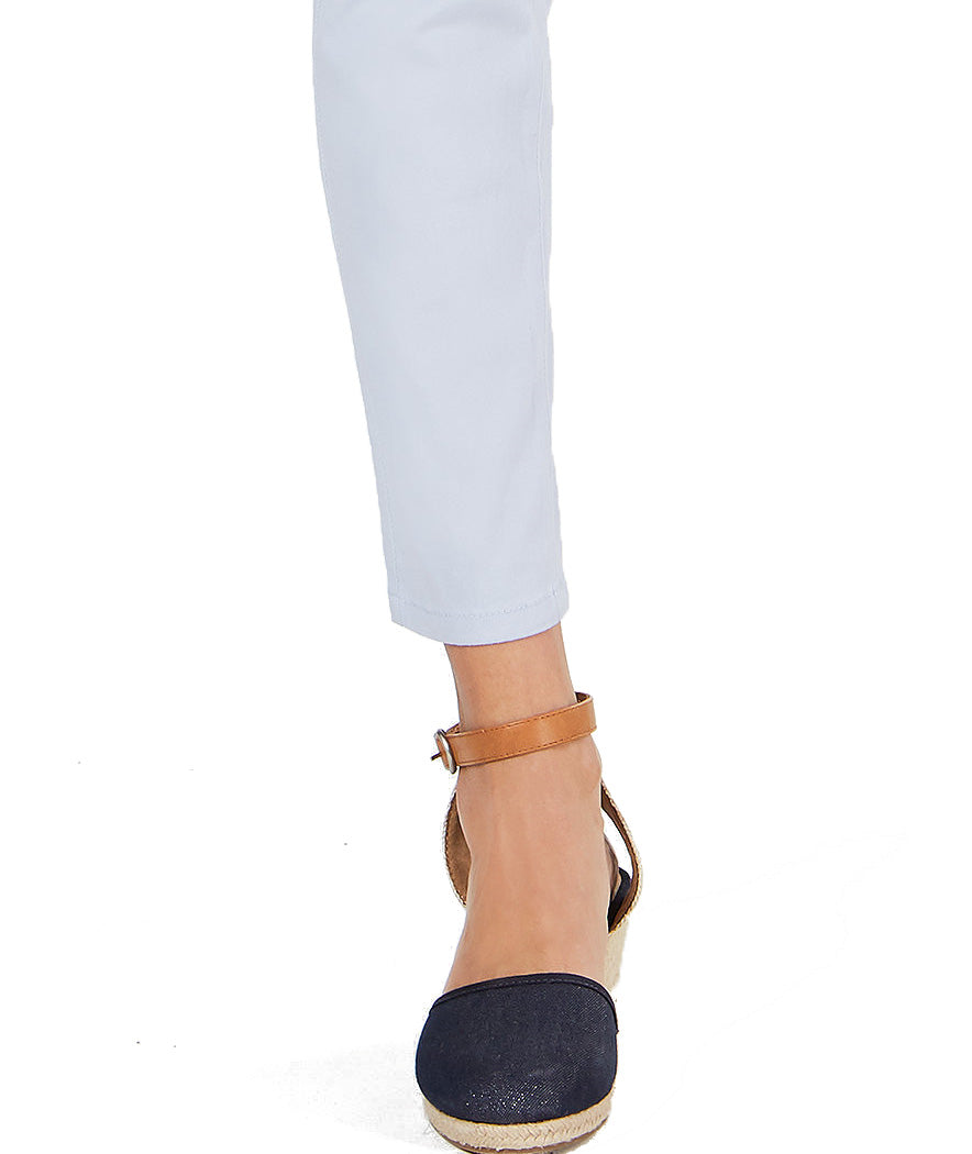 Navy wedge sandals with a tan strap worn with light blue jeans on a white background