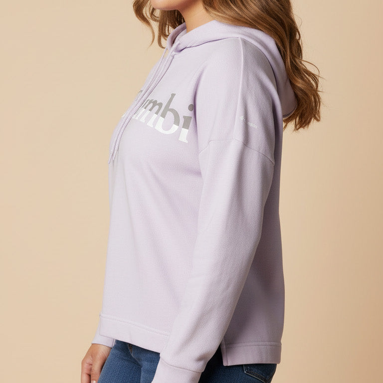 Woman wearing a light purple hoodie with a logo on a beige background