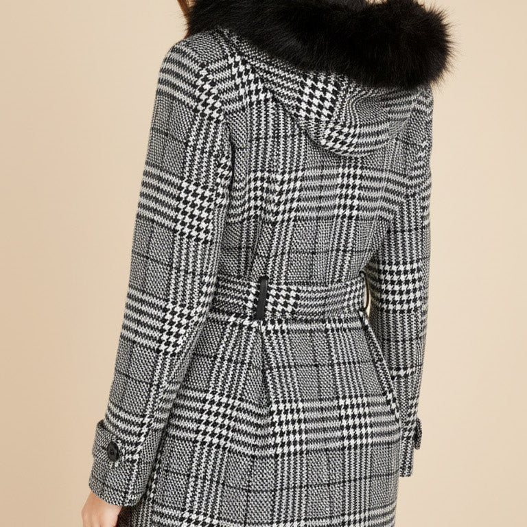 Teen wearing a checkered coat with a fur hood on a beige background