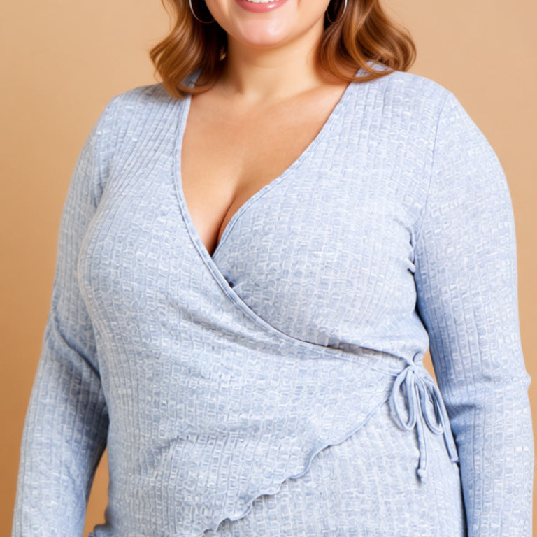 Woman wearing a light blue wrap top and jeans against a beige background