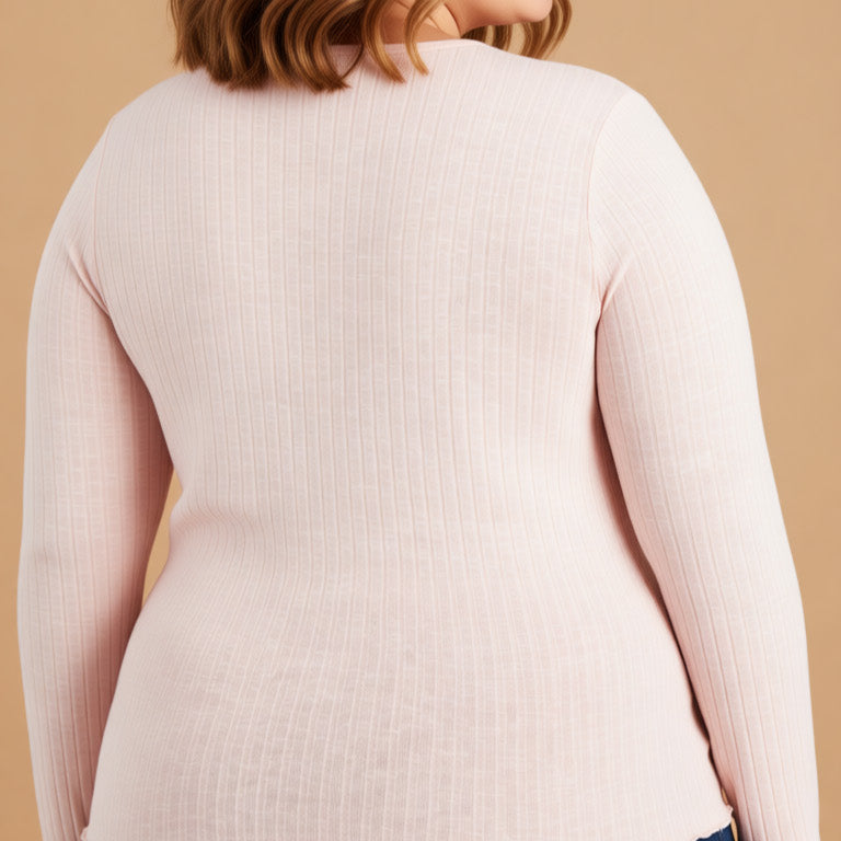 Woman wearing a light pink sweater and blue jeans on a beige background