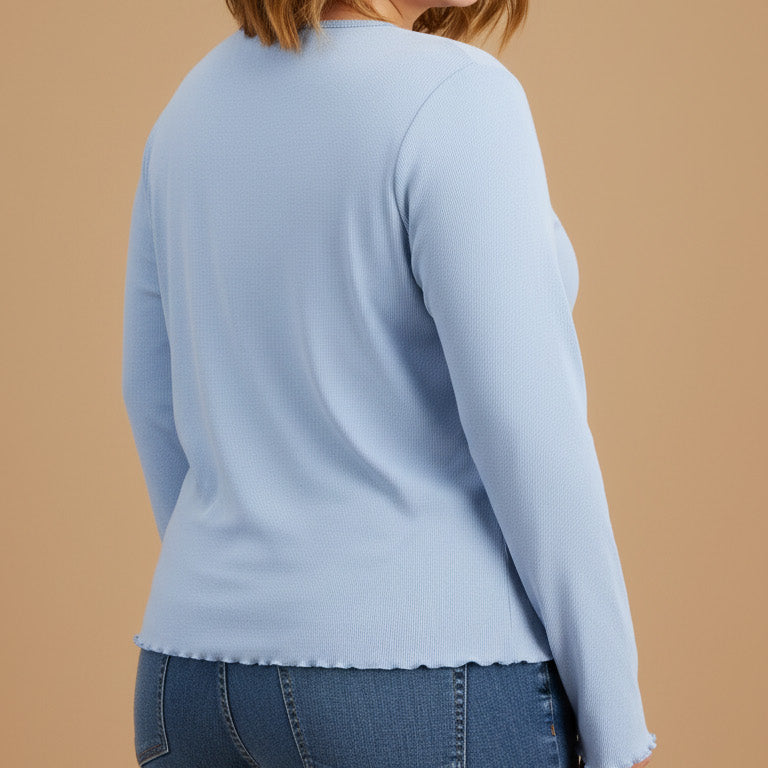 Woman wearing a light blue sweater and jeans on a beige background
