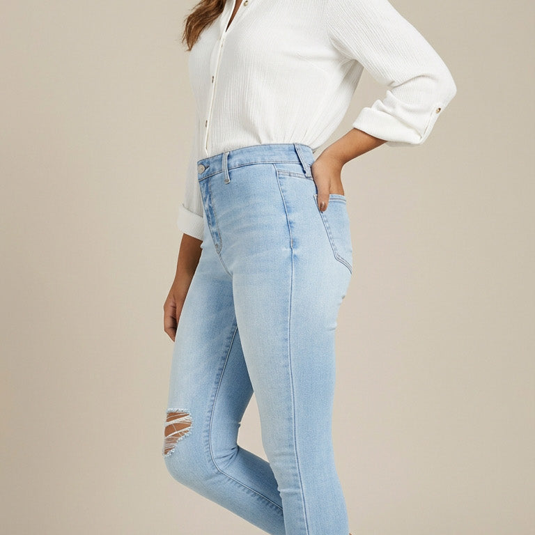 Woman wearing a white shirt and light blue jeans on a beige background