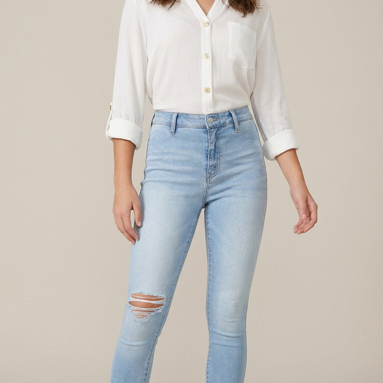 Woman wearing light blue jeans and a white shirt on a beige background