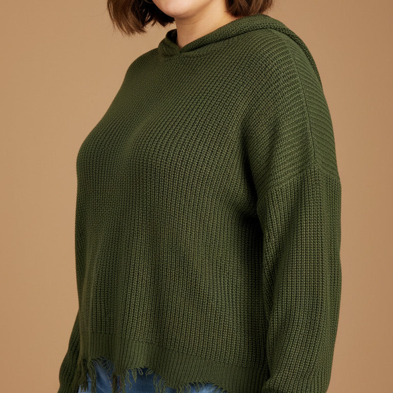 Woman wearing a green sweater and blue jeans on a beige background