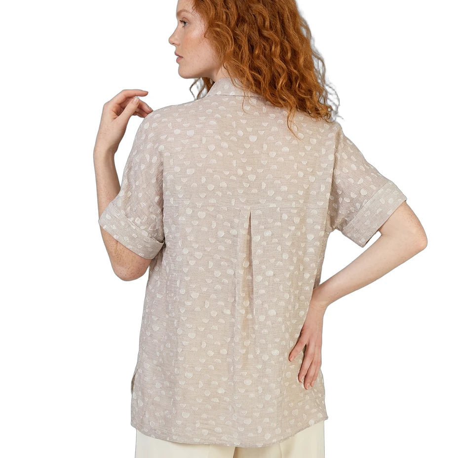Woman wearing a beige patterned shirt on a white background