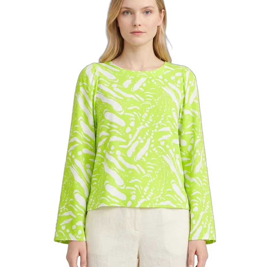 Woman wearing a bright green patterned top on a white background