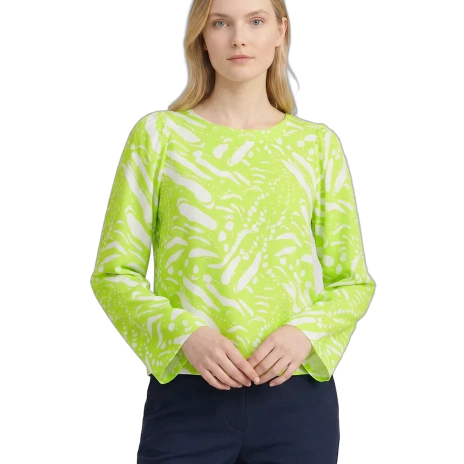 Woman wearing a bright green patterned top on a white background