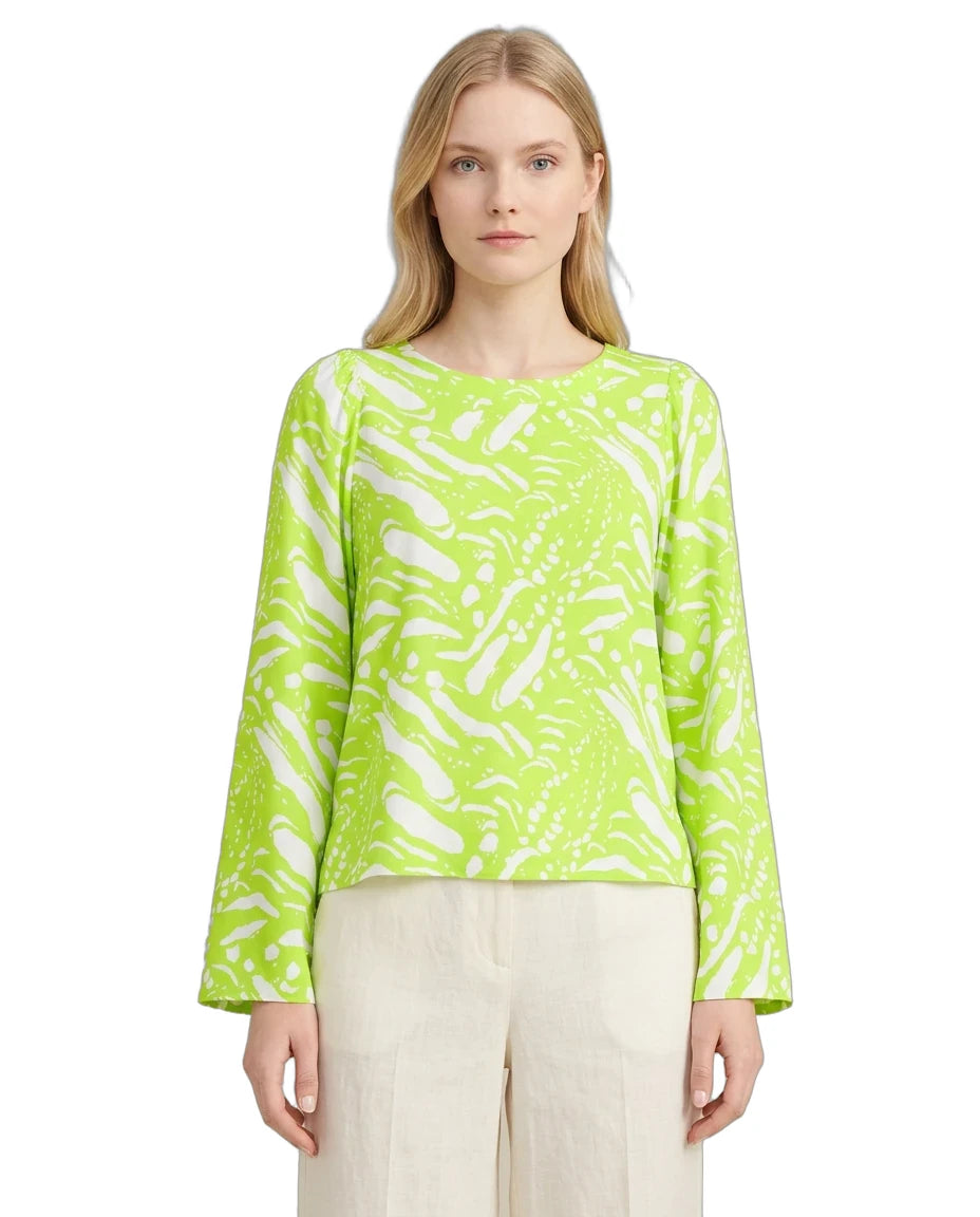 Woman wearing a bright green patterned top on a white background