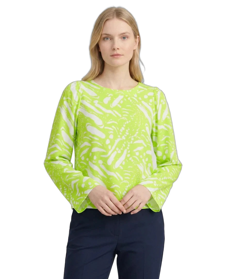 Woman wearing a bright green patterned top on a white background