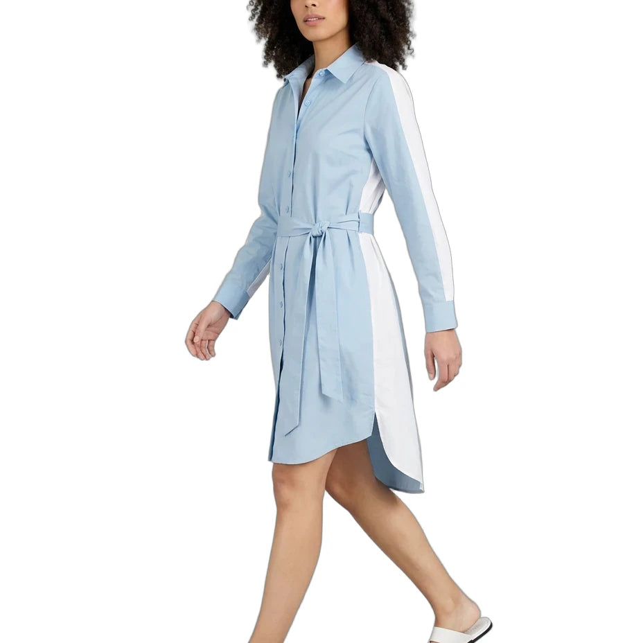 A woman modeling a light blue collared shirt dress with white side panels and a matching waist tie, paired with white slide sandals, on a solid white background.