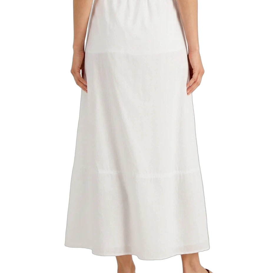 A woman wearing a long white tiered maxi skirt with an elastic waistband, paired with brown flat sandals, shown from the back against a plain white background.