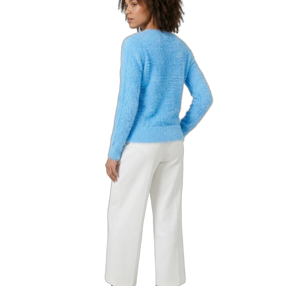 A woman shown from the back wearing a fuzzy light blue long-sleeve sweater, white wide-leg trousers, and black ankle boots against a plain white background.