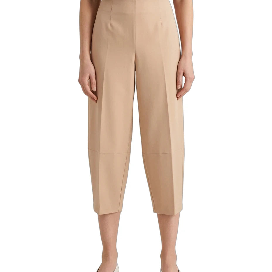A model wearing beige cropped capri pants with a subtle sheen, paired with a black top and white pointed flats, shown against a plain white background.