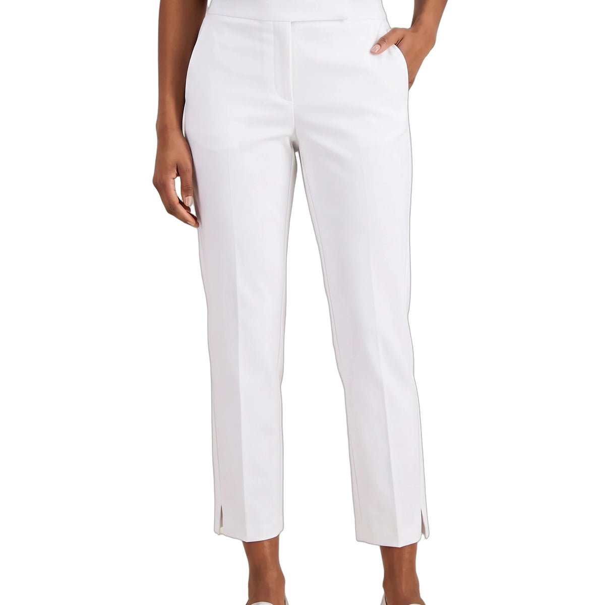 A model wearing white cropped trousers with side slits, paired with a navy top and metallic silver loafers, shown against a plain white background.