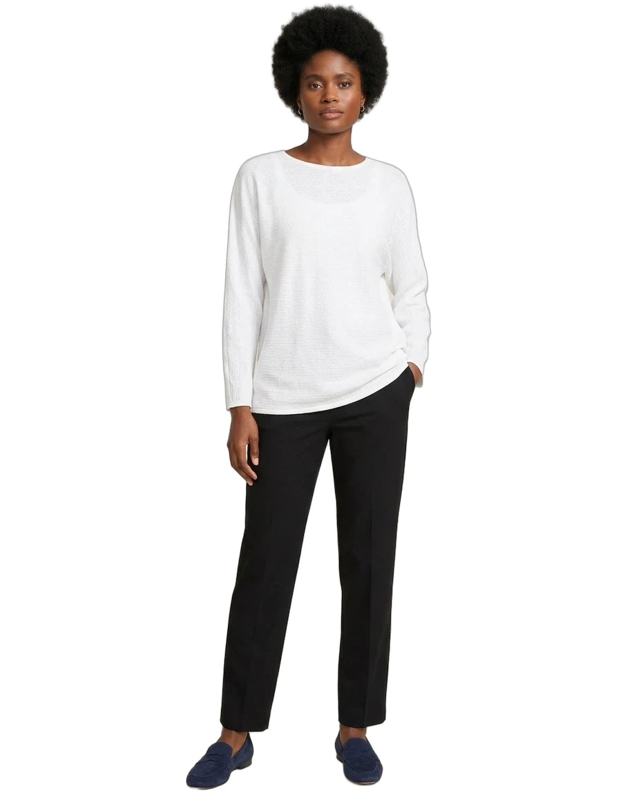 Person wearing a white sweater and black pants on a white background