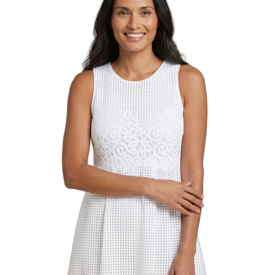 A woman modeling a sleeveless white eyelet dress with a textured, openwork pattern against a solid white background.