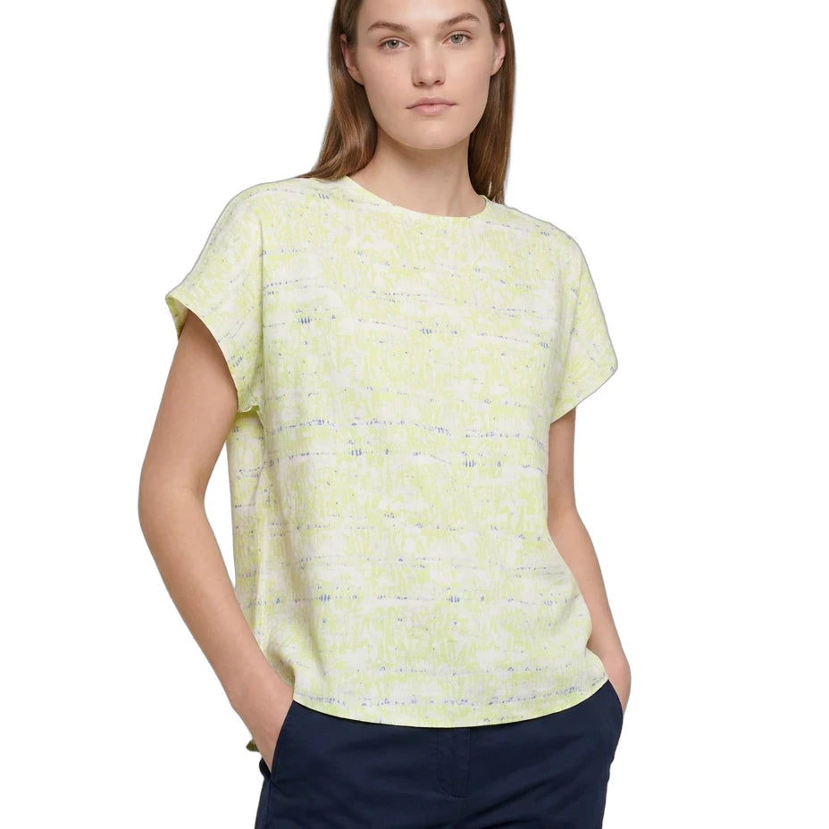A woman modeling a pale yellow-green short-sleeve knit top with a subtle horizontal textured pattern, paired with navy blue pants, against a plain white background.