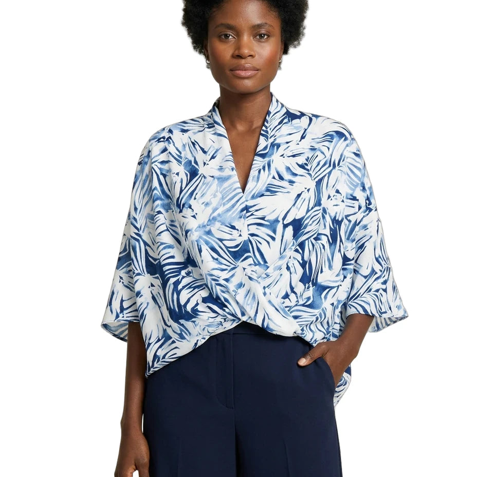 Woman wearing a blue and white patterned blouse with navy pants on a white background