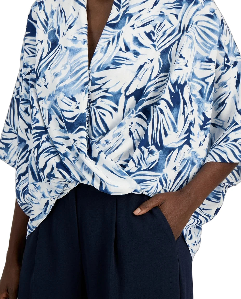 Blue and white patterned top worn by a person with a dark background