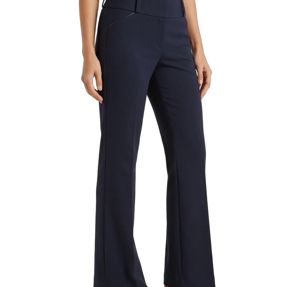 A model wearing a pair of dark navy blue high-waisted flared trousers, paired with a cream top and tan loafers, shown against a plain white background.