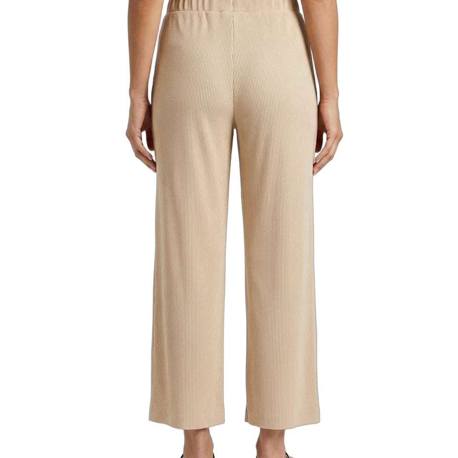 A person shown from the back wearing high-waisted, wide-leg cropped pants in a light beige or sand color, paired with a black top and flat sandals, against a plain white studio background.