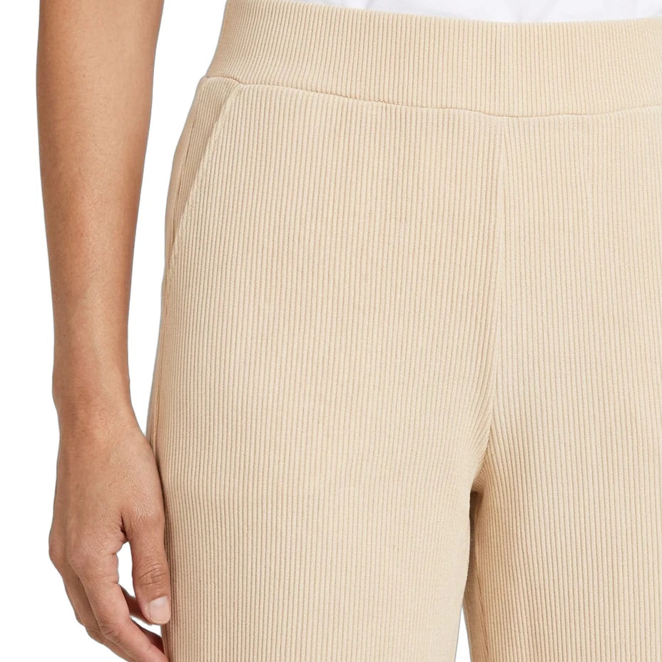 Close-up of a person wearing ribbed knit pants in a light beige or cream shade, paired with a white top. The photo focuses on the texture and fit of the pants, with a plain white background.