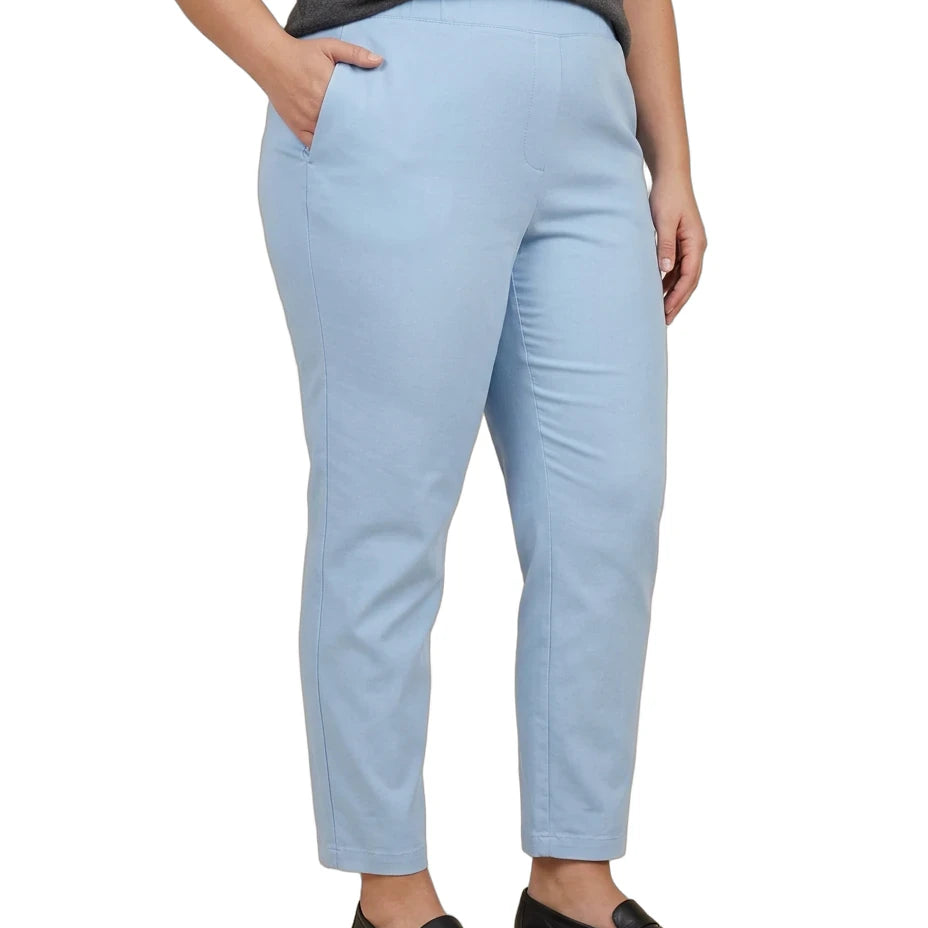 A person wearing light blue cropped trousers with a dark gray top and black loafers, shown from the waist down against a plain white background.