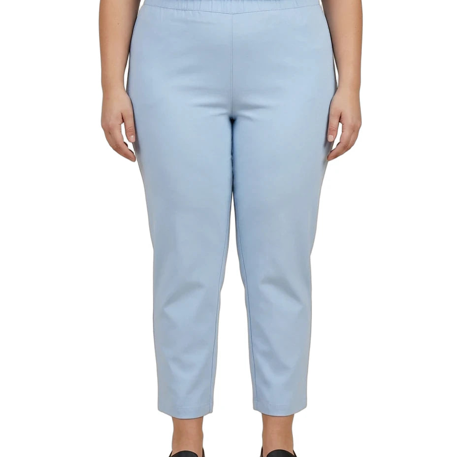 A person wearing light blue cropped pants with a dark gray top and black slip-on shoes, shown from the chest down against a plain white background.