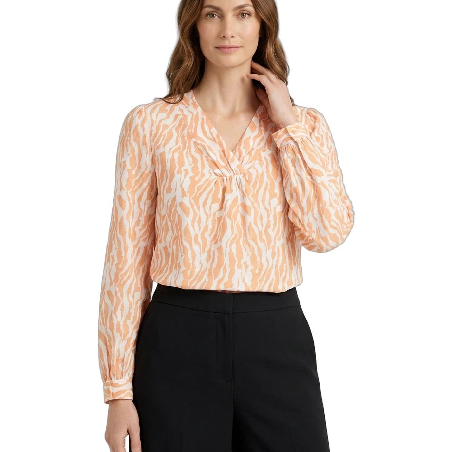 Woman wearing a patterned blouse and black pants on a white background