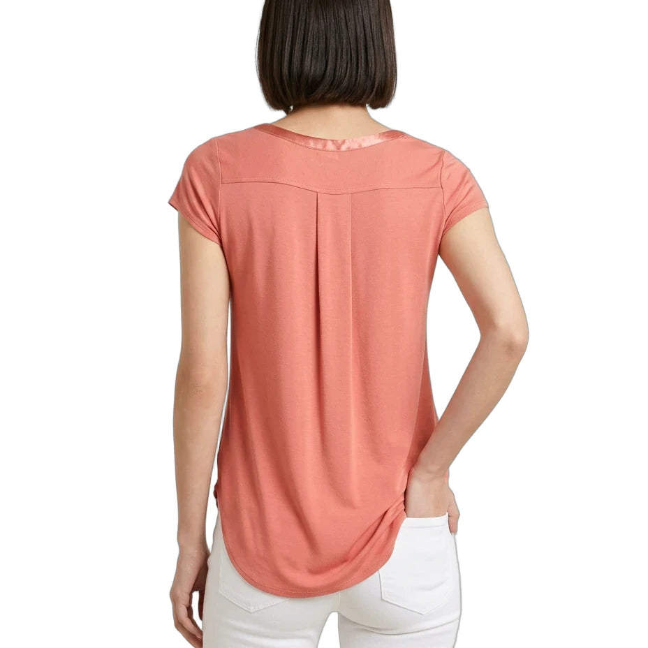 Woman wearing a coral-colored t-shirt and white pants on a white background