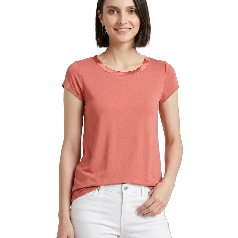 Woman wearing a coral t-shirt and white pants on a white background
