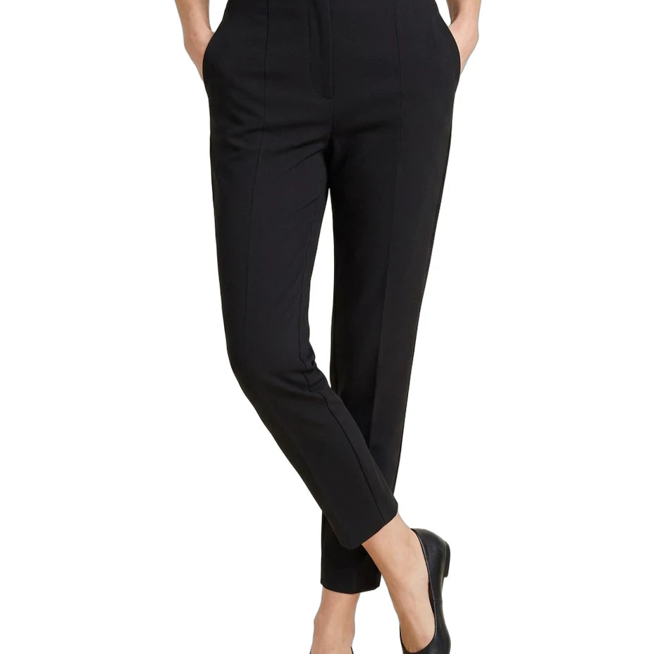 A model wearing black cropped trousers with a navy blue top and black pointed flats, shown from the waist down on a white background.