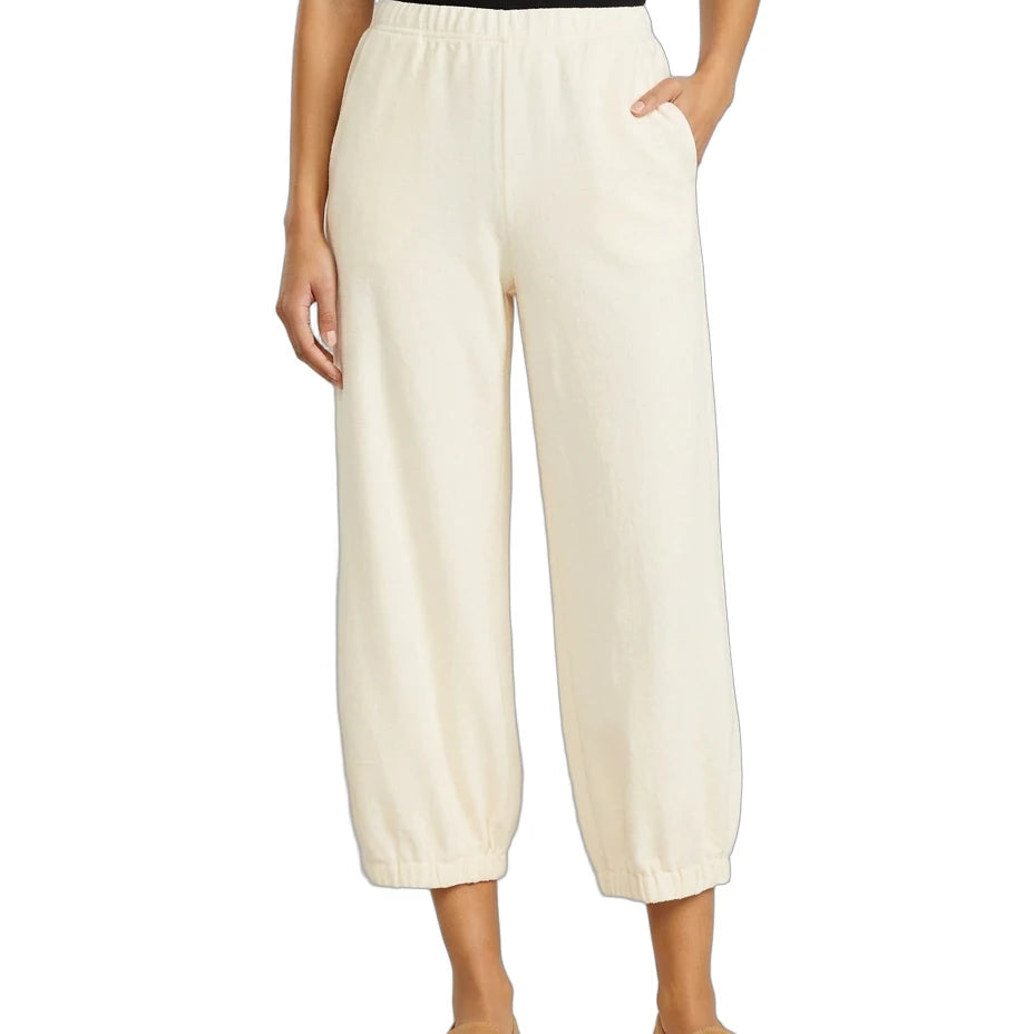 A model wearing a pair of cream-colored cropped wide-leg pants with an elastic waistband and side pockets, paired with a black top and tan loafers, against a plain white background.