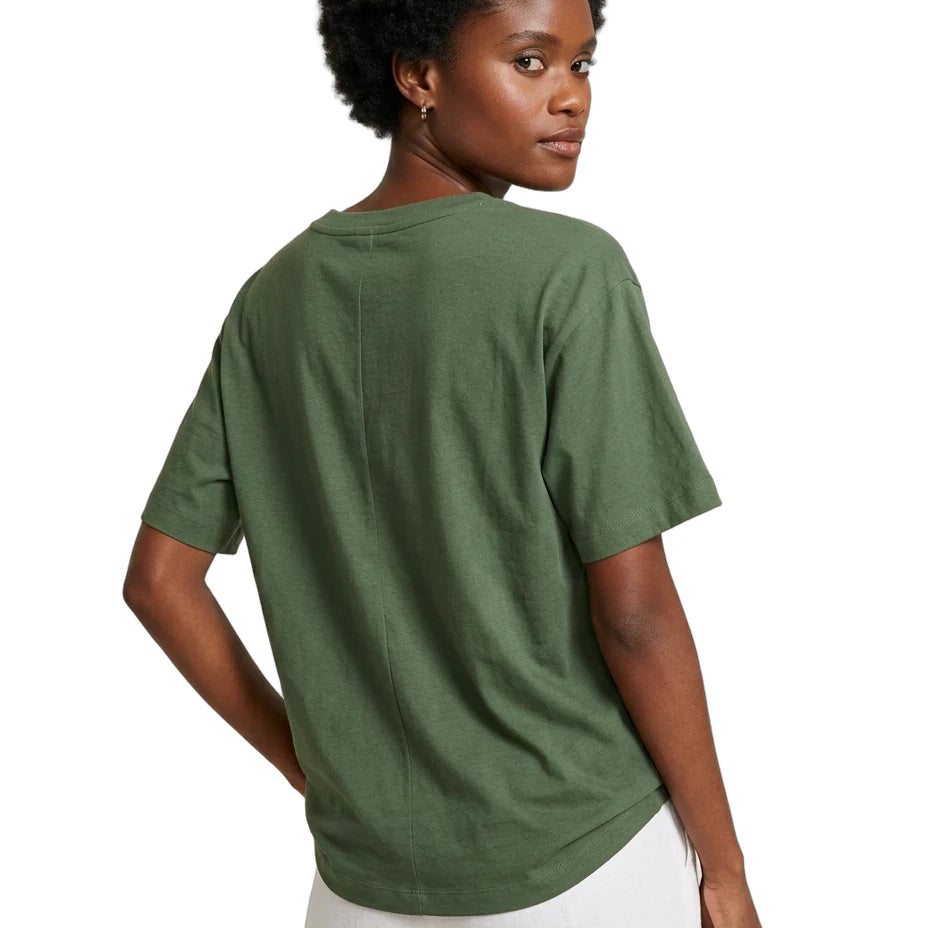 A woman shown from the back wearing an oversized short-sleeve crewneck t-shirt in olive green, paired with white pants, against a plain white background.