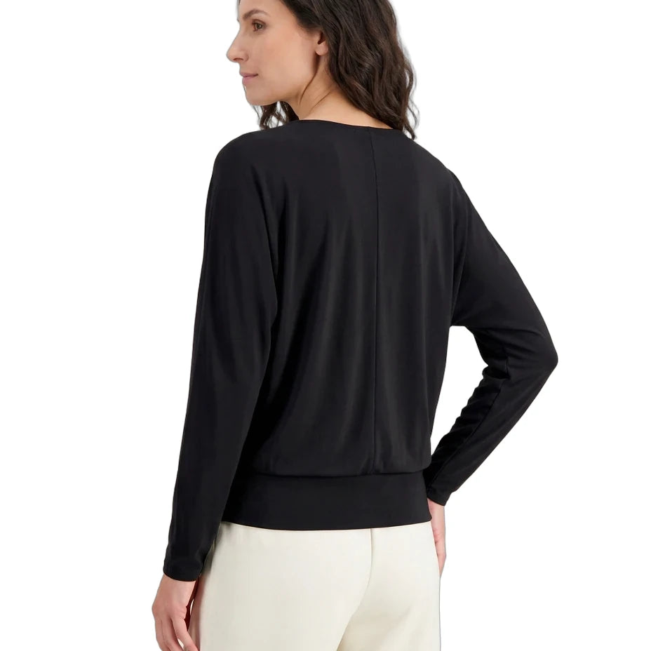 Woman wearing a black long-sleeve top and white pants on a white background