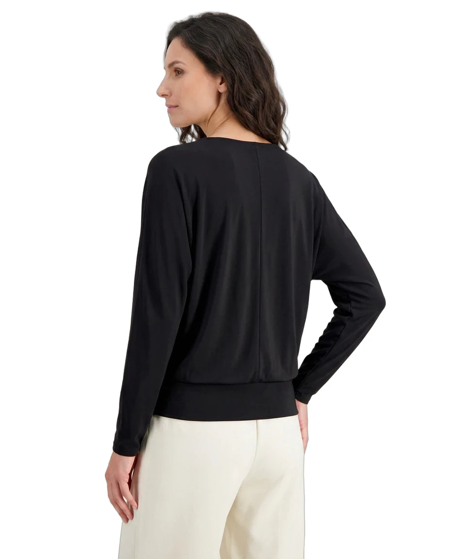 Woman wearing a black long-sleeve top and white pants on a white background
