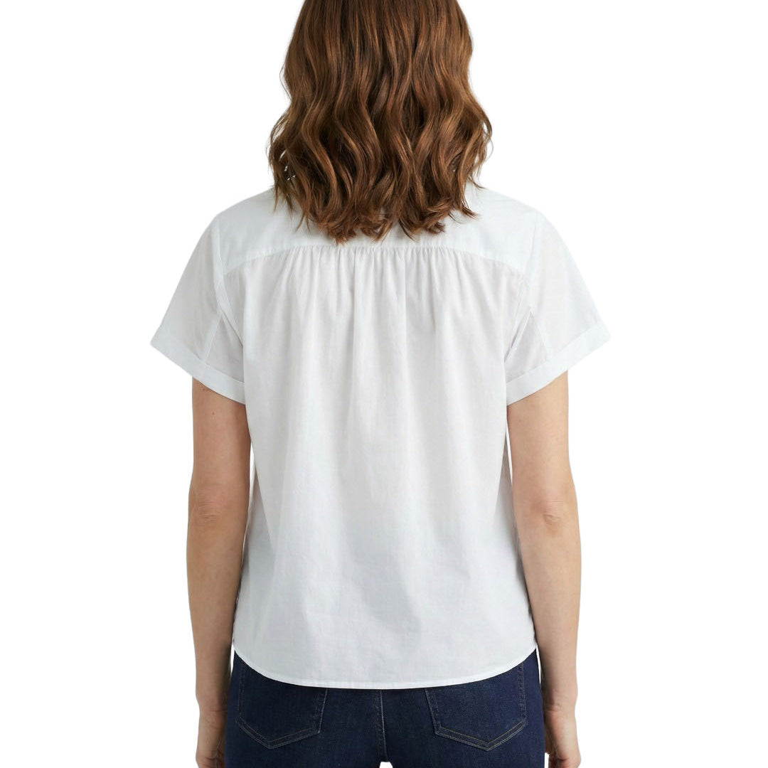 Woman wearing a white blouse and dark jeans on a white background
