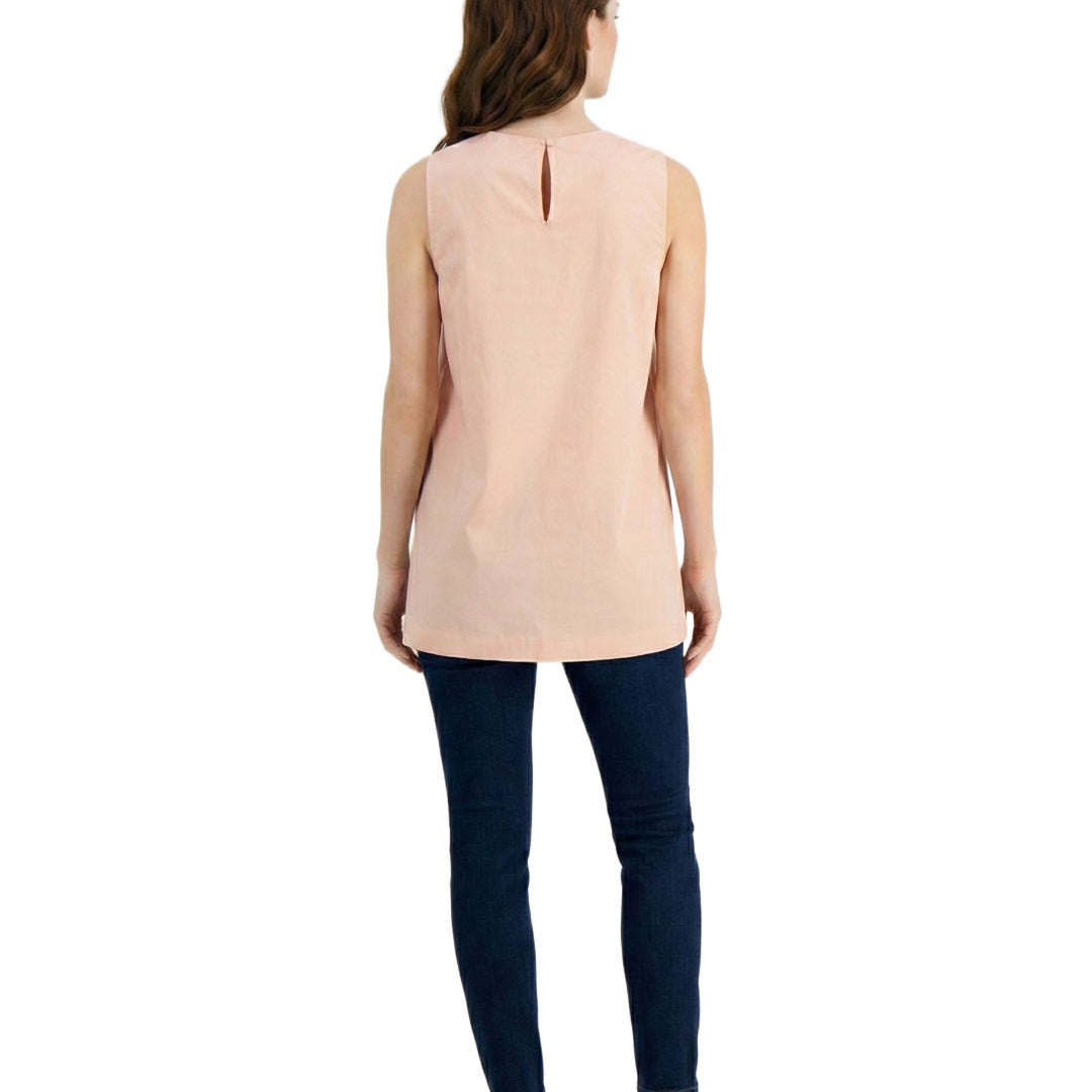 Woman wearing a sleeveless beige top and dark blue jeans on a white background