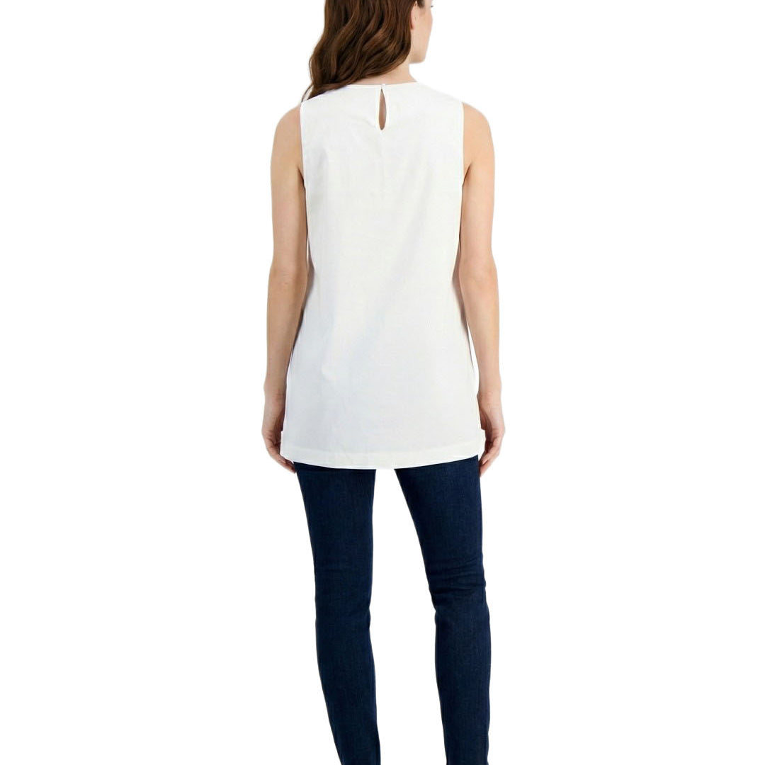 Woman wearing a white sleeveless top and dark blue pants on a white background
