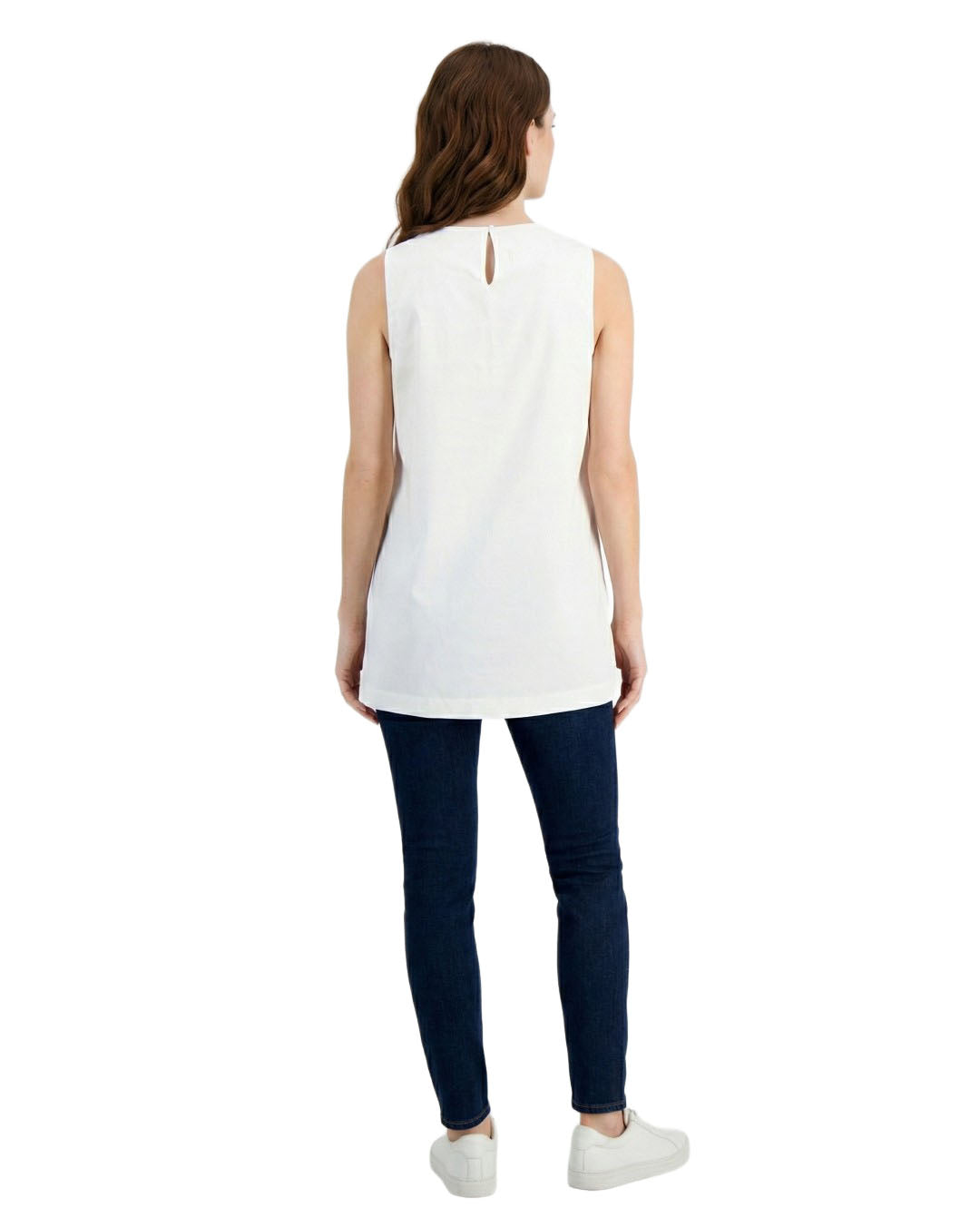 Woman wearing a white sleeveless top and dark blue pants on a white background