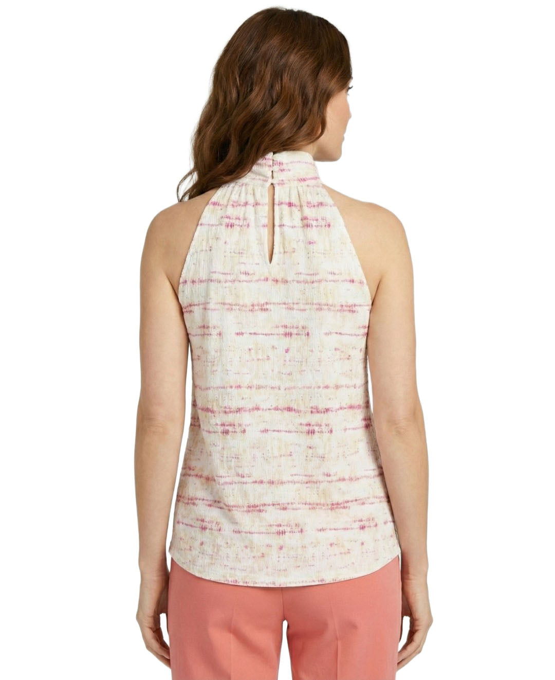 Woman wearing a sleeveless patterned top and pink pants on a white background